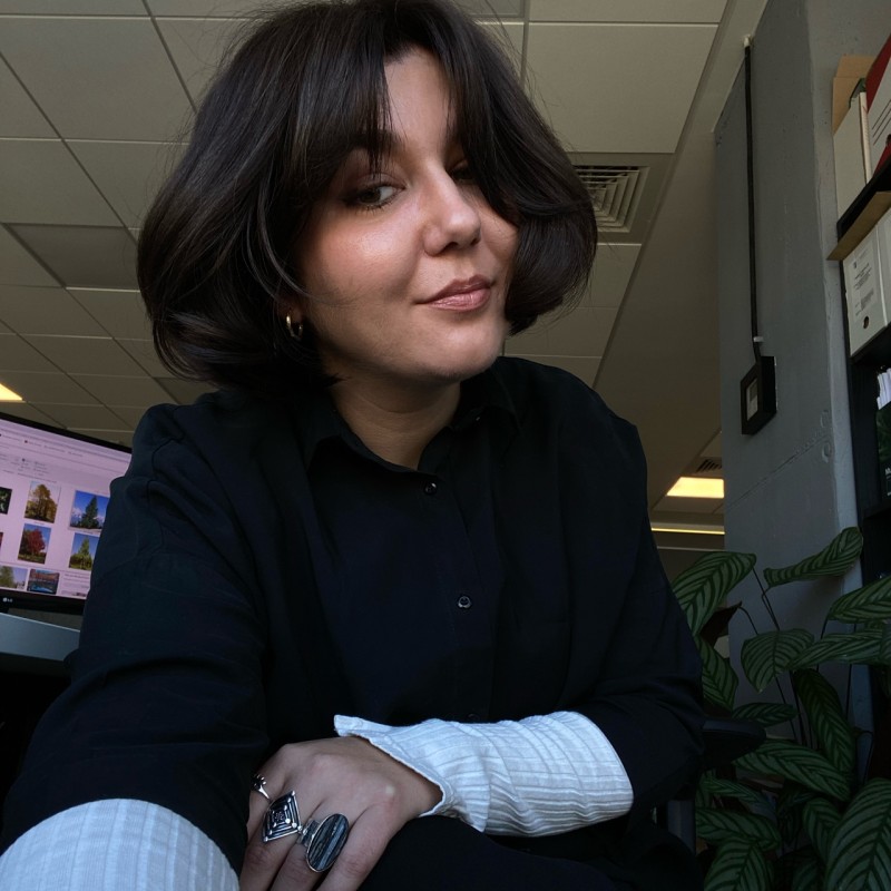 Luciana Zeca în spațiul ei de lucru, alături de o plantă și planșe de proiect